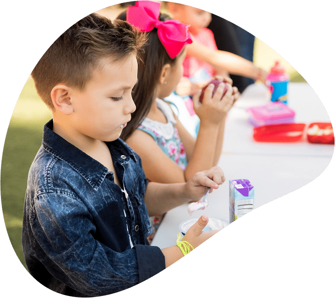 Child eating snack at outdoor table.